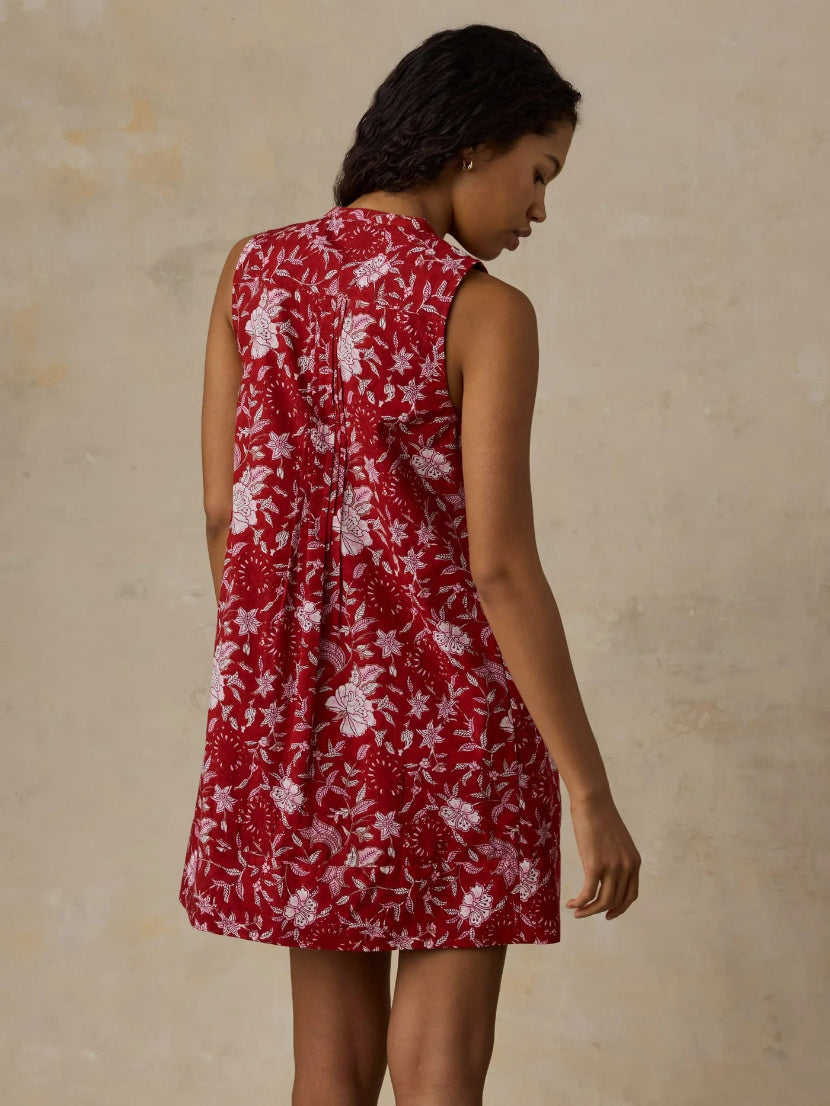 Woman wearing a red floral dress against a beige background