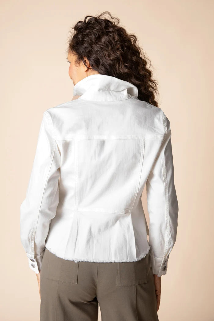 A woman shown from the back wearing a white long-sleeve collared shirt and taupe pants against a solid beige studio background.