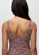 Back view of a person wearing a floral dress with thin straps on a plain background