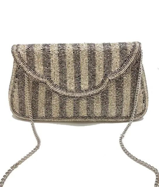 A beaded clutch bag with vertical stripes in beige, brown, and black, featuring a silver chain strap, shown against a plain white background.