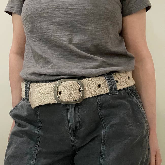 woman wearing a wool  beige belt with black jeans and a grey tshirt 