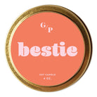 A round gold metal tin candle lid with a coral pink label reading 'G/P bestie' and 'SOY CANDLE 4 OZ.' on a white background.