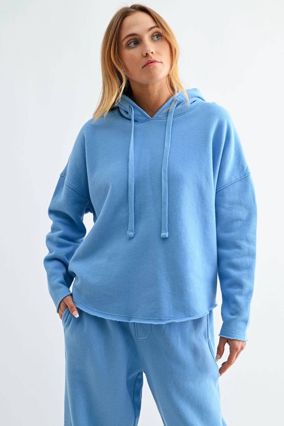 Woman wearing a blue hoodie and pants on a white background