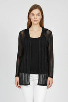 Woman wearing a black sheer jacket over a black top and white pants on a white background