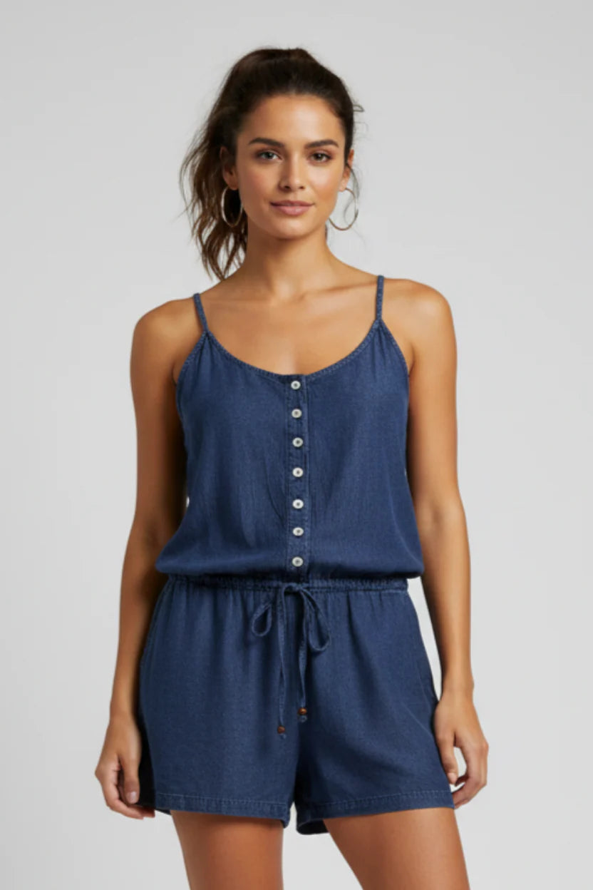 Woman wearing a blue romper with button details on a plain background