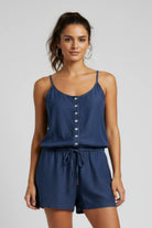 Woman wearing a blue romper with button details on a plain background