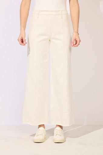 Person wearing light-colored pants and white sneakers on a plain background