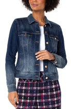 Woman wearing a blue denim jacket over a white shirt and plaid skirt on a white background