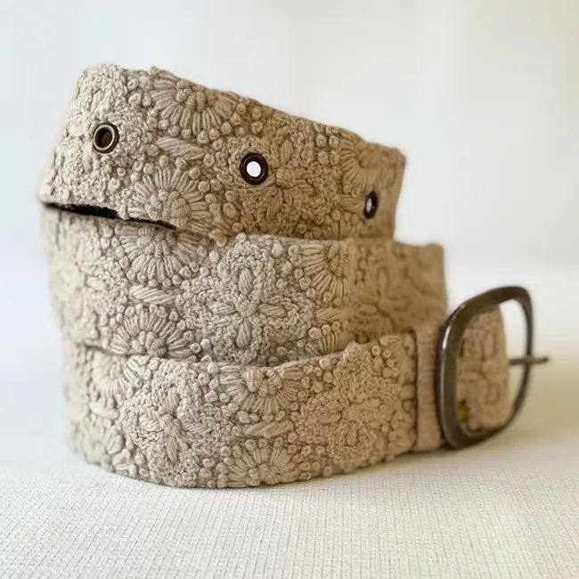 Beige lace belt with a metal buckle on a light background