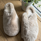 Beige rabbit fur slippers on a cozy rug