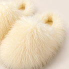 Close-up of the shaggy faux fur texture on the ivory slippers