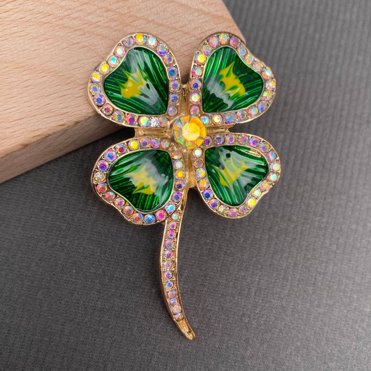 Four-leaf clover brooch with gemstones on a gray surface