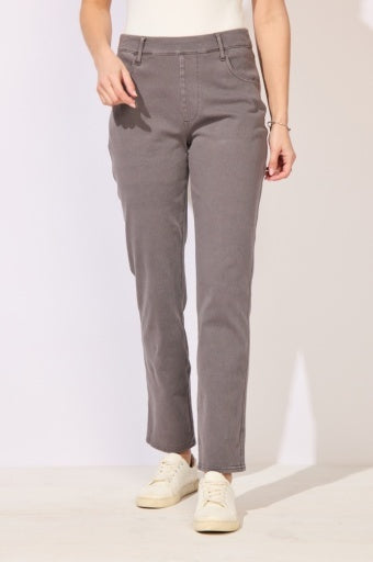 A person wearing straight-leg gray pants with a white top and white sneakers, standing against a plain light background.