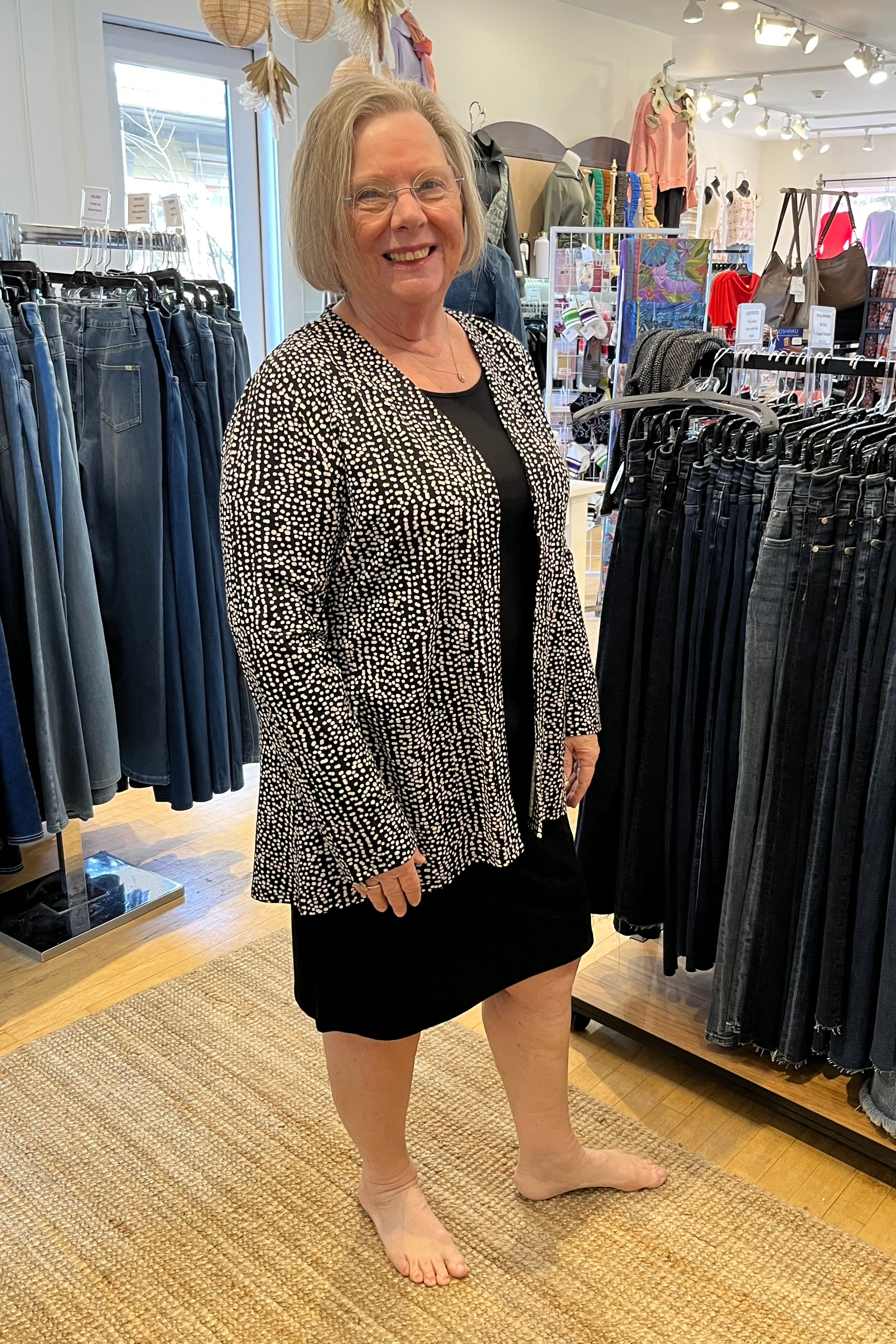 Habitat Core Travel Short Everything Dress in black, sleeveless knit shift layered under a black and white cardigan, styled in store