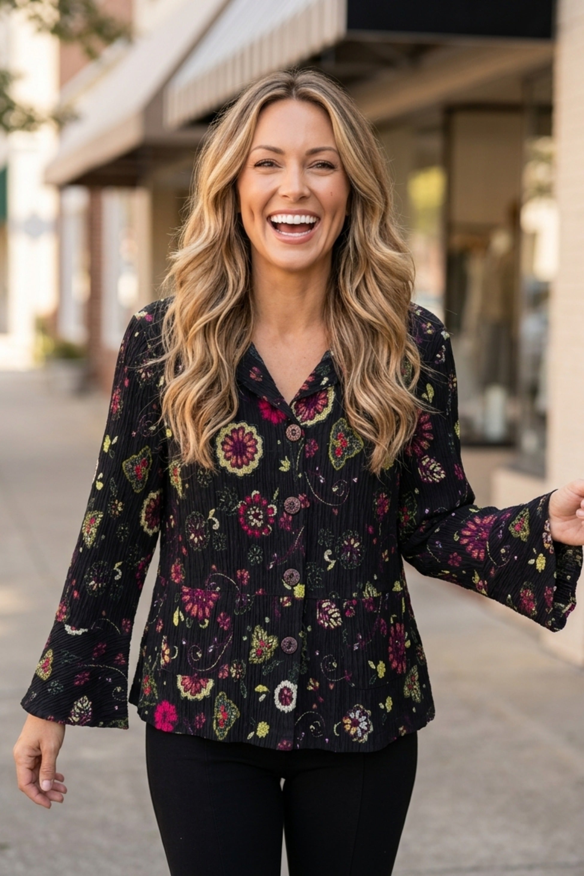 Woman wearing the Habitat Crinkle Floral Flounce Jacket in black floral print with flounce cuffs, styled outdoors