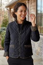 Woman wearing the Habitat Reversible Print Quilt Puffer Coat with the solid black side out and animal print trim at pockets and cuffs