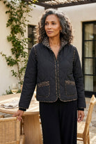 Habitat Reversible Print Quilt Puffer Coat in black, zipped, worn on an outdoor patio