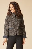 Woman wearing the Habitat reversible quilted puffer coat, animal print side out with stand collar, zip front and solid black cuffs
