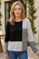 Woman wearing the Habitat Yin Yang Block Party Sweater in Mist, black and grey color-block crewneck with jeans