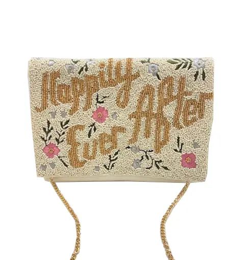 A rectangular clutch bag covered in beige beads with the phrase 'Happily Ever After' in brown script, decorated with pink flowers and green leaves, featuring a gold chain strap.