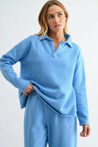 Woman wearing a light blue outfit with a matching top and pants on a white background