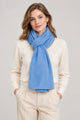 Model wearing the In Cashmere Classic Cashmere Scarf in Blue Skies, a soft light blue 100% cashmere