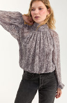 Close-up of the shirred mock neckline and abstract grey print