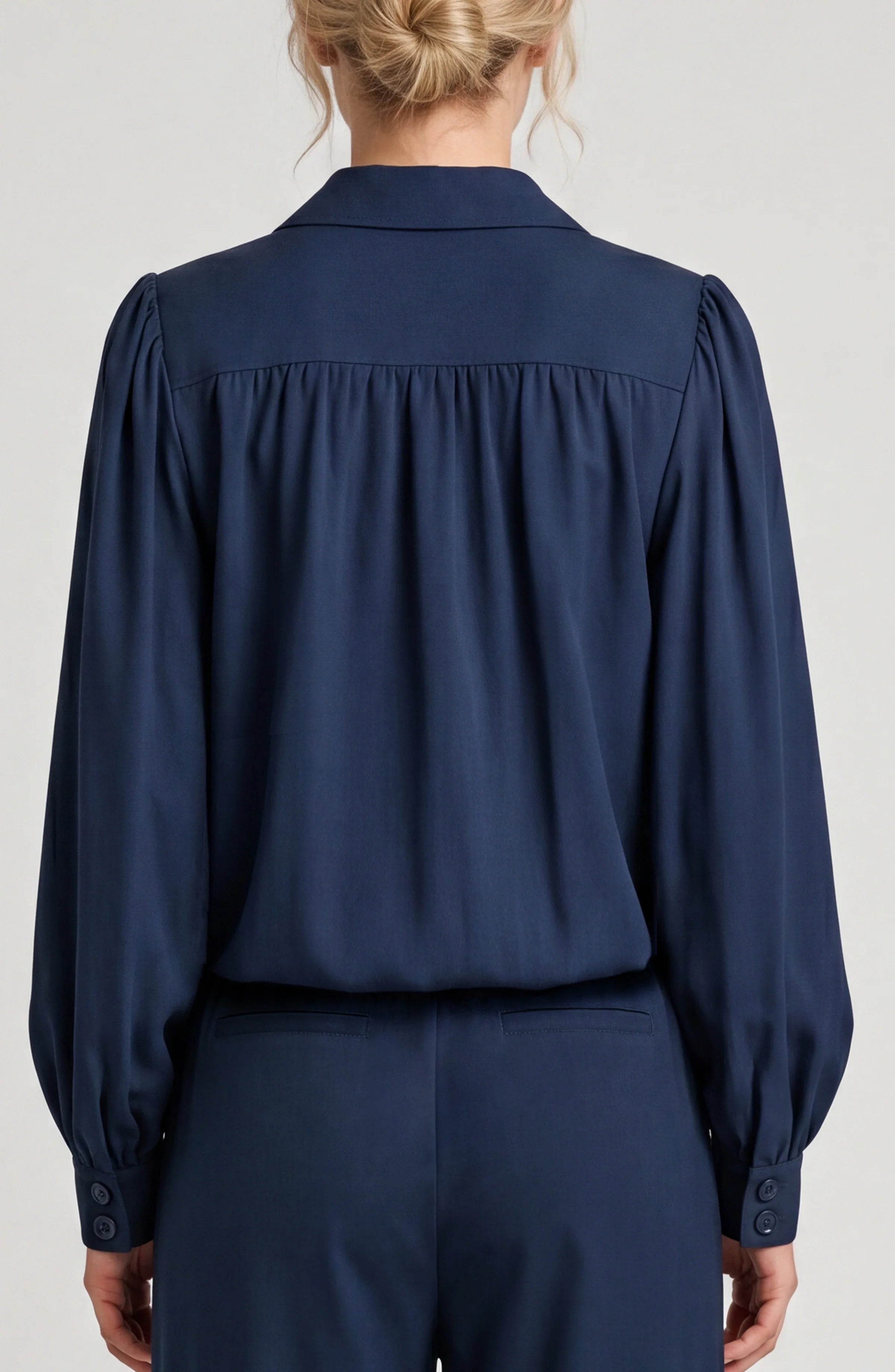 Navy blue blouse worn by a person on a light gray background