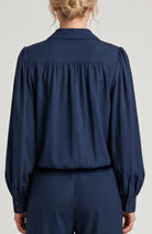 Navy blue blouse worn by a person on a light gray background