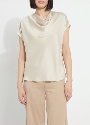 Model wearing the Lysse Yasmin Drape Neck Sleeveless Blouse in travertine cream satin with tan trousers
