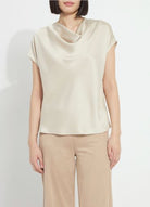 Model wearing the Lysse Yasmin Drape Neck Sleeveless Blouse in travertine cream satin with tan trousers