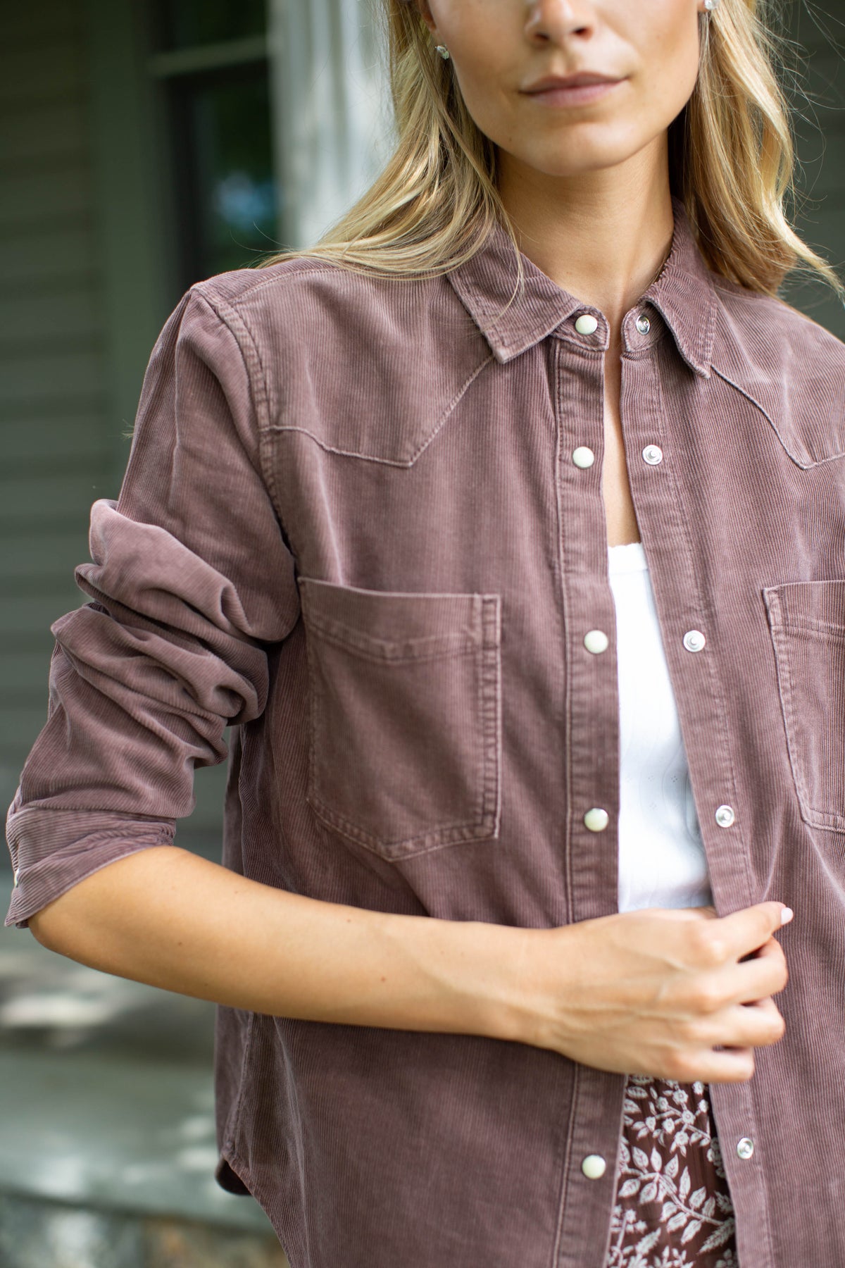 Woman wearing the MAREA western shirt in brown corduroy with sleeves pushed up, layered over a white tee