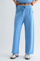woman wearing light blue wide leg pant with white sneakers