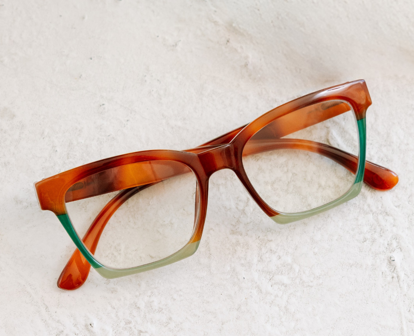 Peepers Birdie reading glasses in tortoise with a mint colorblock base, styled flat lay