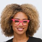 Woman wearing Peepers Page blue light reading glasses in pink and tan