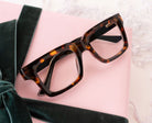 Peepers Spotlight reading glasses in tortoise and black, styled flat lay