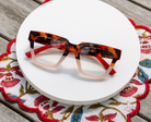 Peepers Take A Bow reading glasses in tortoise and blush, styled flat lay