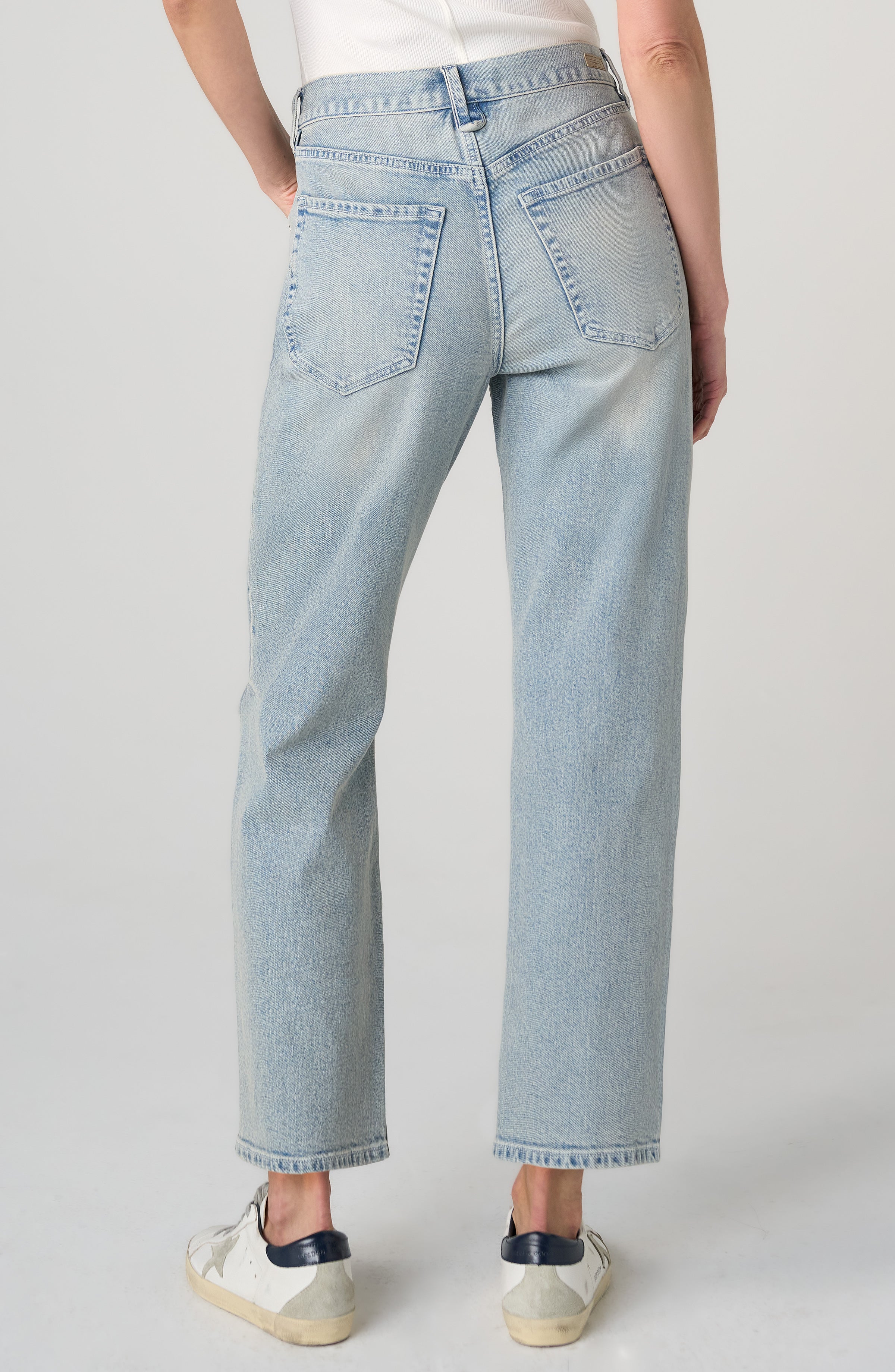 Light wash blue denim jeans shown from the back on a model, featuring a straight-leg fit and classic five-pocket design, paired with white sneakers against a light gray studio background.