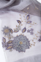 Close-up of floral embroidery on the grey sheer scarf