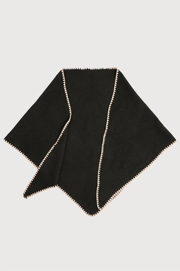 Black knitted triangle shawl laid flat with whipstitch edge
