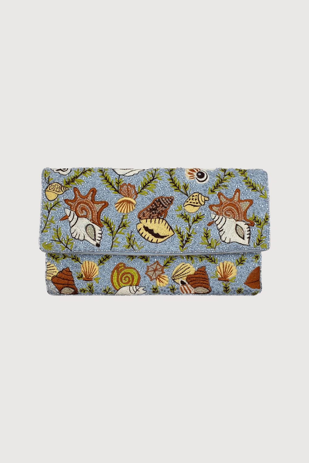 A folded clutch bag featuring a detailed, colorful embroidered seashell and sea plant pattern on a dusty blue background, set against a solid light gray studio backdrop.