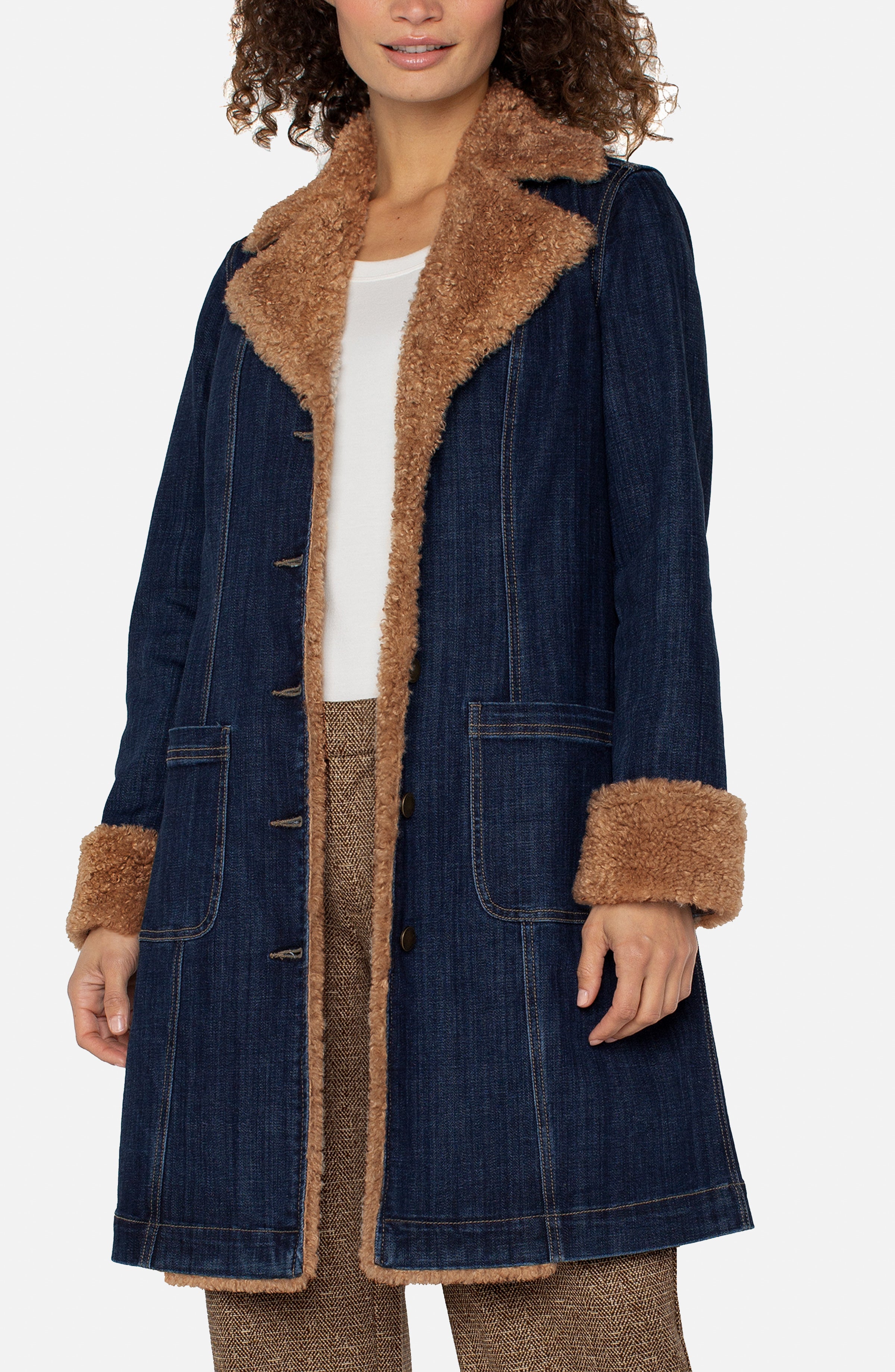 Woman wearing a denim coat with brown fur trim on a white background