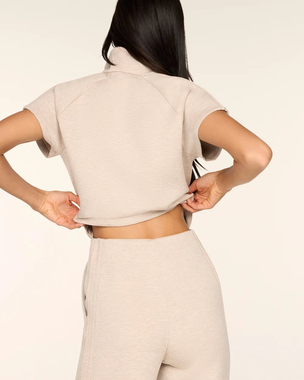 Back view of the Spanx AirEssentials Pintuck Half Zip Jumpsuit in Bone Heather with the top lifted to show the hidden back opening for easy bathroom breaks