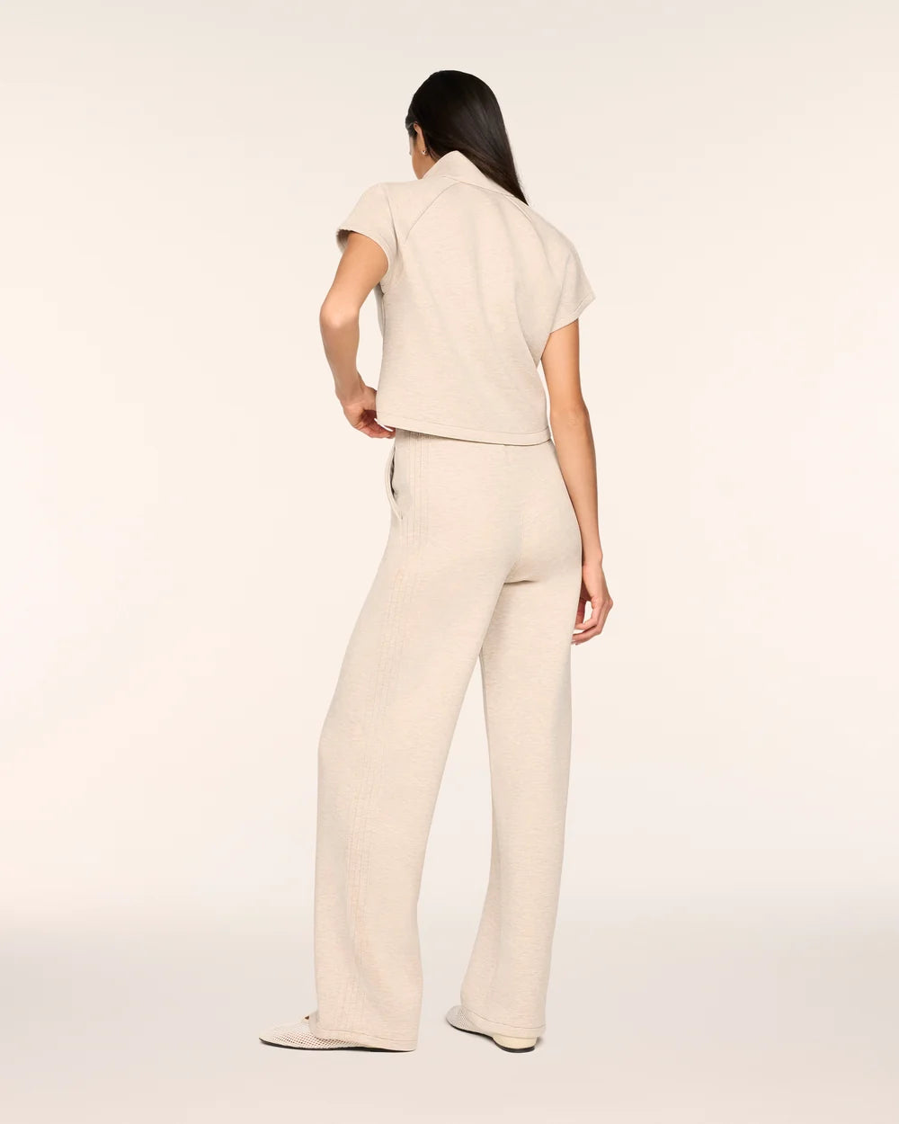 Full-length back view of the Spanx AirEssentials Pintuck Half Zip Jumpsuit in Bone Heather showing the stand collar, short sleeves, side pocket and relaxed wide-leg fit