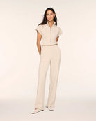 Full-length front view of a woman wearing the Spanx AirEssentials Pintuck Half Zip Jumpsuit in Bone Heather with short sleeves, half-zip collar, pintucked relaxed wide legs and ballet flats