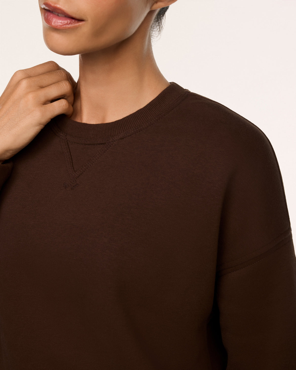 Close-up of the ribbed crew neckline on the SPANX Cotton Fleece Crewneck in Umber Root brown