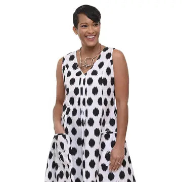 Tulip Clothing Women's Poppie Dress in Meko, woman modeling a sleeveless white dress with a black irregular spotted pattern, featuring a split neckline and side pockets, set against a plain white background