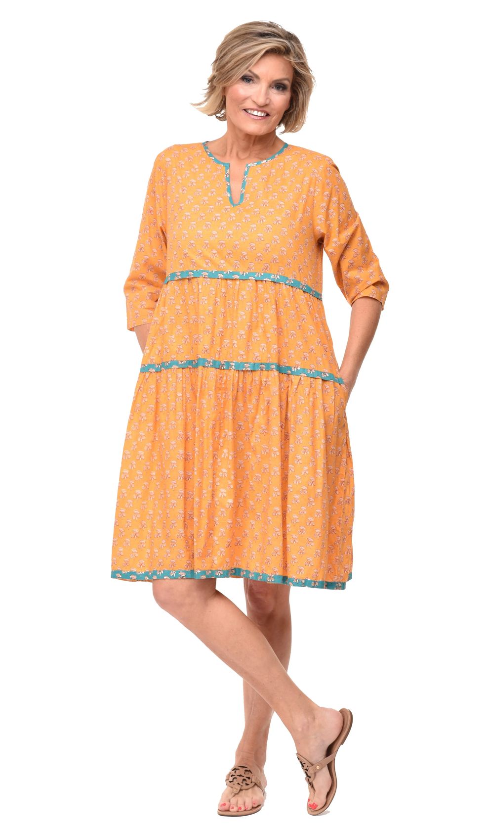 Woman wearing an orange dress with blue trim on a white background