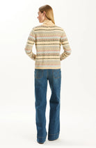 Back view of a woman wearing the Tyler Boe Jen Fair Isle Turtleneck Sweater in a multicolor striped Fair Isle pattern with blue jeans