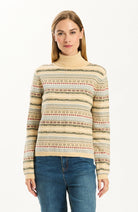 Woman wearing the Tyler Boe Jen Fair Isle Turtleneck Sweater in a cream multicolor Fair Isle pattern with blue jeans